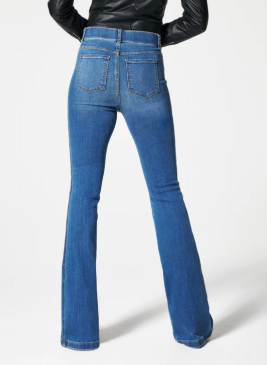 Back View of the model wearing the SPANX Ocean Flare Jeans showing the back pockets and long seamed pants.