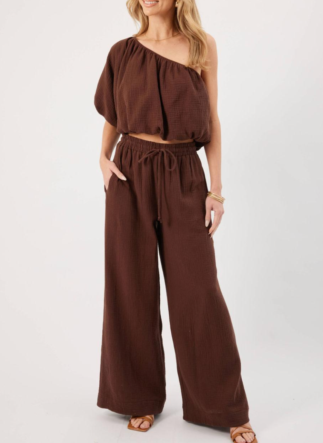 Model wearing brown KP Lina Top with one shoulder detail and bubble hem along with matching pants.