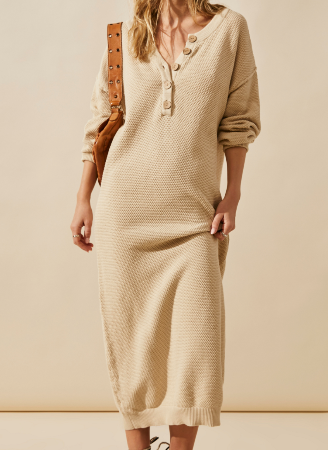 Front view of the model wearing the FP Sammy Knit Henley Dress. Her hand grabbing one side of the dress to show the texture of the dress.
