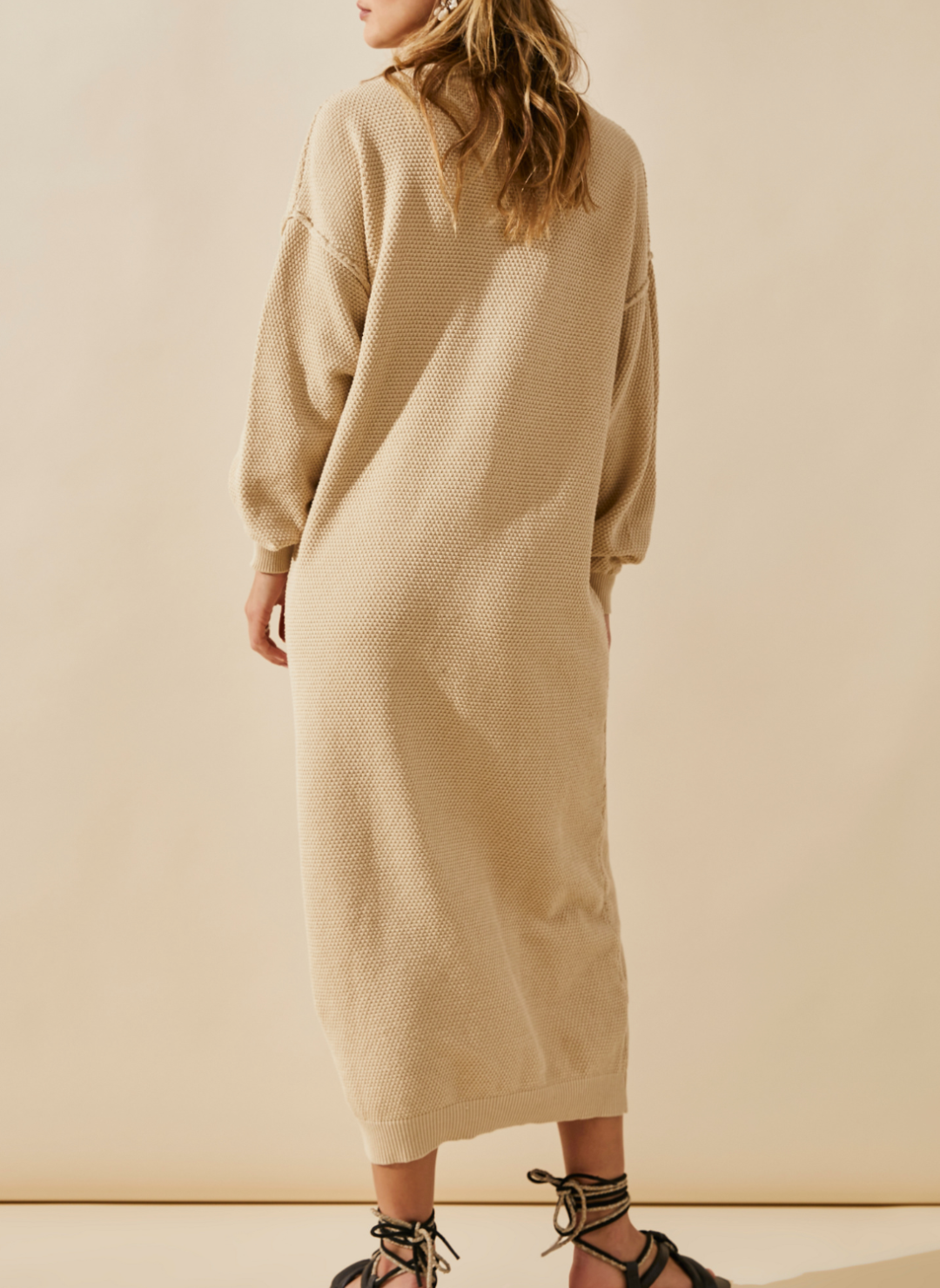 Back side of the model wearing the FP Sammy Knit Henley Knit Dress with the models arms to her side showing the length of the dress.