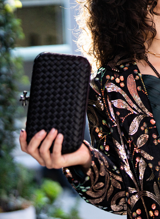 Image showing an up close view of model holding the Black - Top Shelf Clutch. Model is outside.