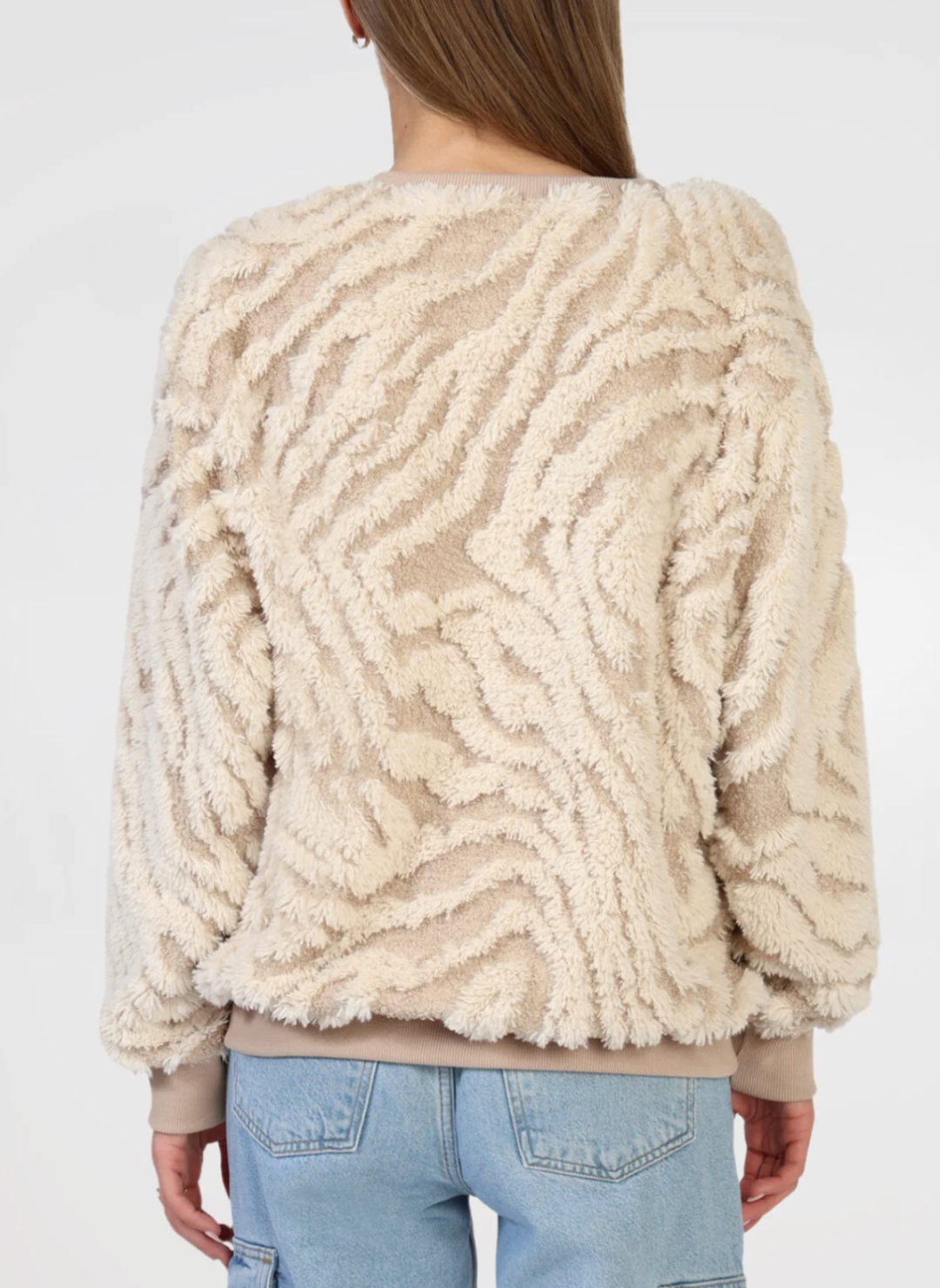 Back view of model wearing tan and cream textured sweater. Models arms are by her side. White background.