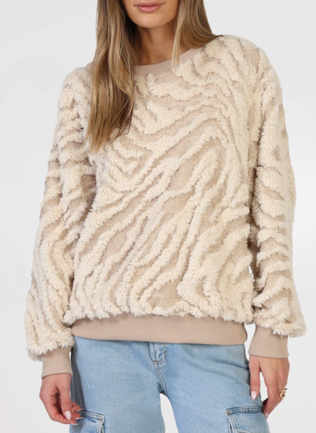 Front view of model wearing tan and cream textured sweater with tan band around bottom and bottom of sleeves.