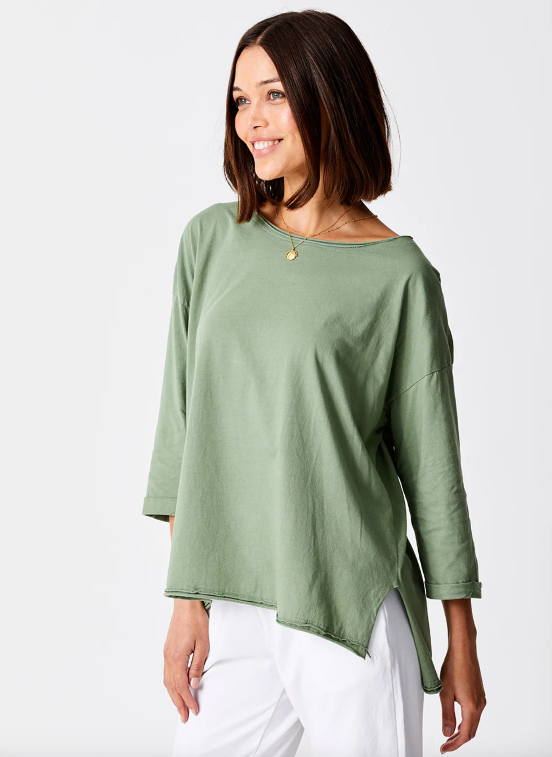 front view of model wearing the Suzy D Jardine Knit 3/4 Sleeve Top paired with white pants. Model is standing in front of white background.