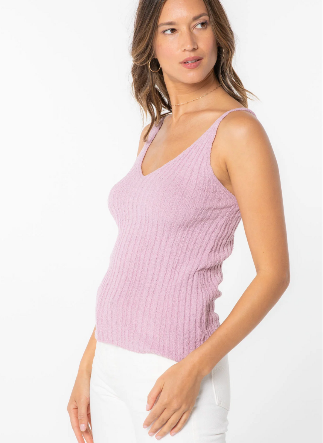 Side view of model wearing the Sheena Sweater Knit Rib Tank paired with white pants. Model is standing informs of white background.
