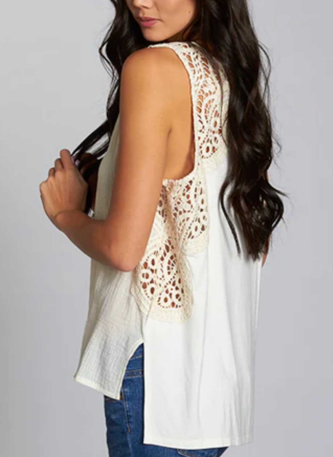 Woman wearing a sleeveless ivory tank top with intricate crochet lace detailing on the shoulders and upper back. The Lovestitch Crochet Tank features a soft cotton gauze front, knit jersey back, and relaxed boho-inspired fit—perfect for boutique-style summer outfits.