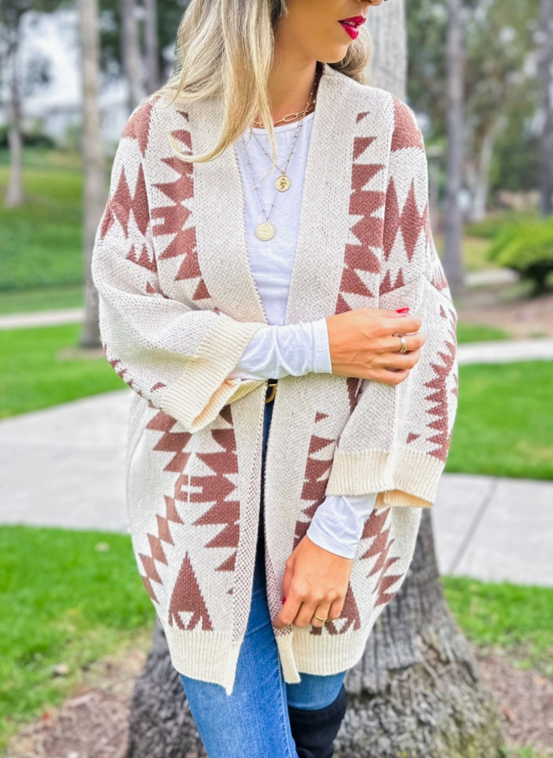 Model is wearing southwestern printed open cardigan either one arm crossed to show the 3/4 length sleeves.