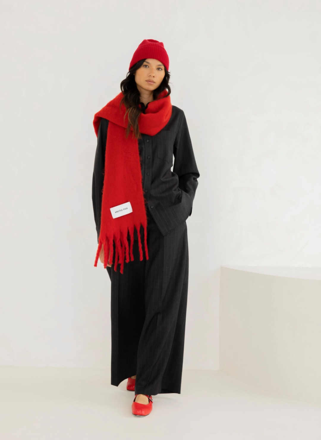 Model is wearing a red beanie to match the solid red colored scarf.