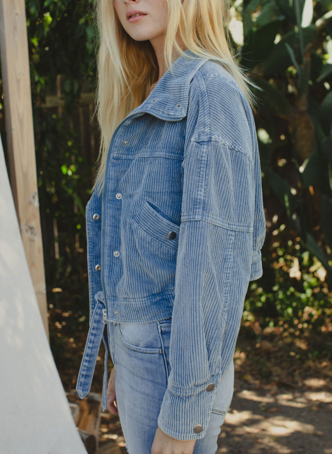 Full side view of model wearing Trailblazer Cord Crop Jacket. Model is also outside and wearing denim pants.