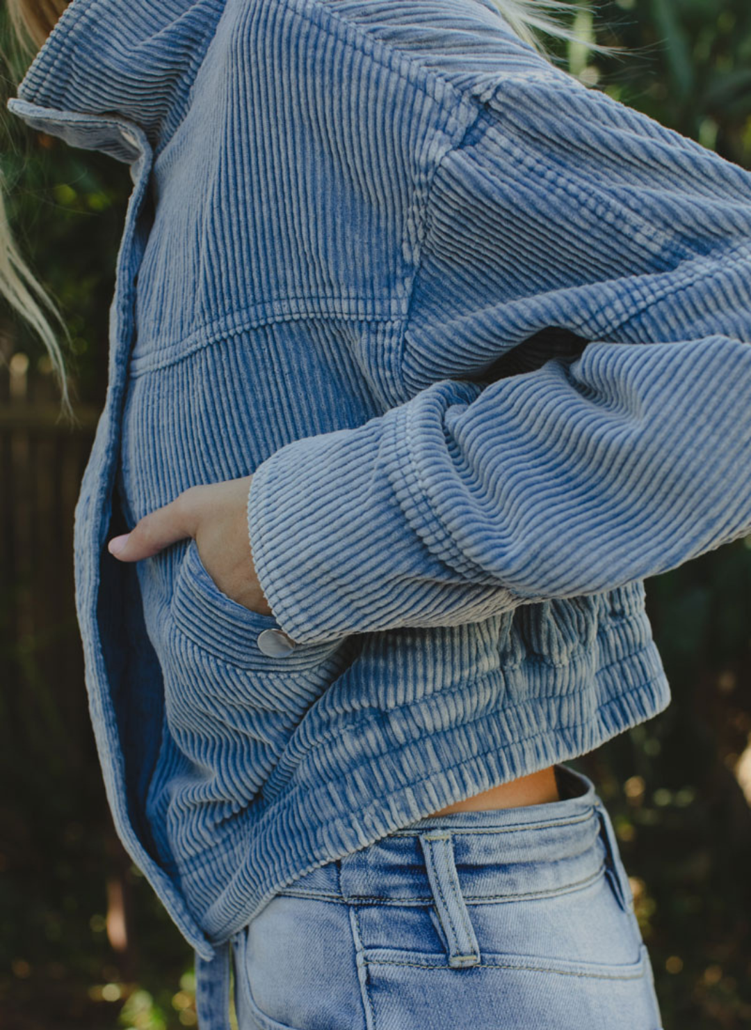 Side view of model wearing Trailblazer Cord Crop Jacket. Model is also outside and wearing denim pants.