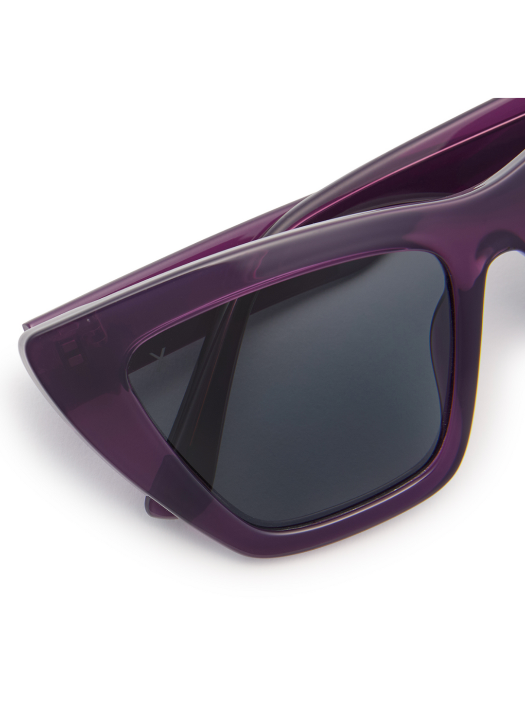 Image shows up close view of grey lenses on purple colored sunglasses frame.
