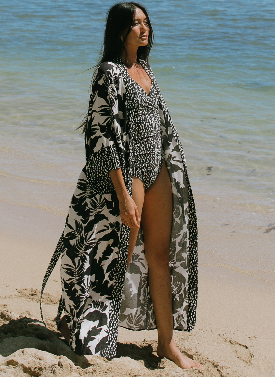 Woman walking on the beach wearing a tropical black-and-white kimono with contrast printed trim.