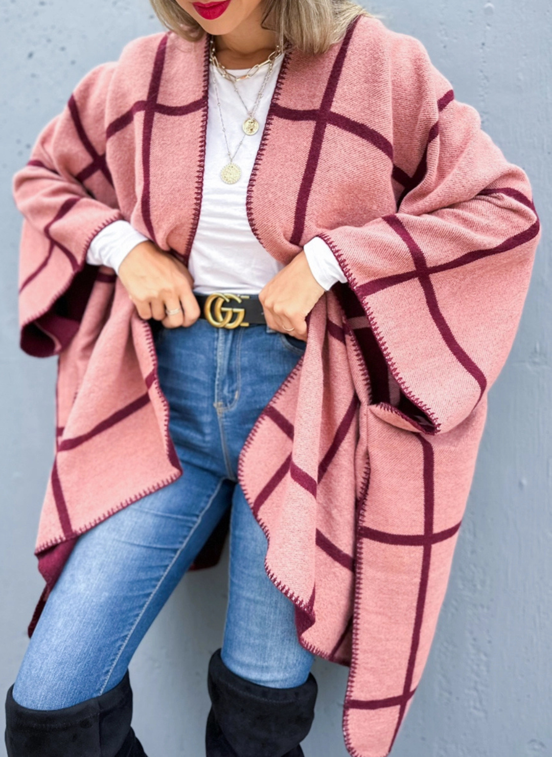 Front view of the model wearing the Reversible Grid Cardigan paired with denim pants, a black belt, and black boots.
