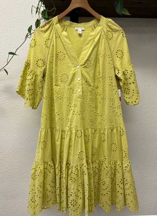 Yellow lace dress on a hanger against a neutral wall
