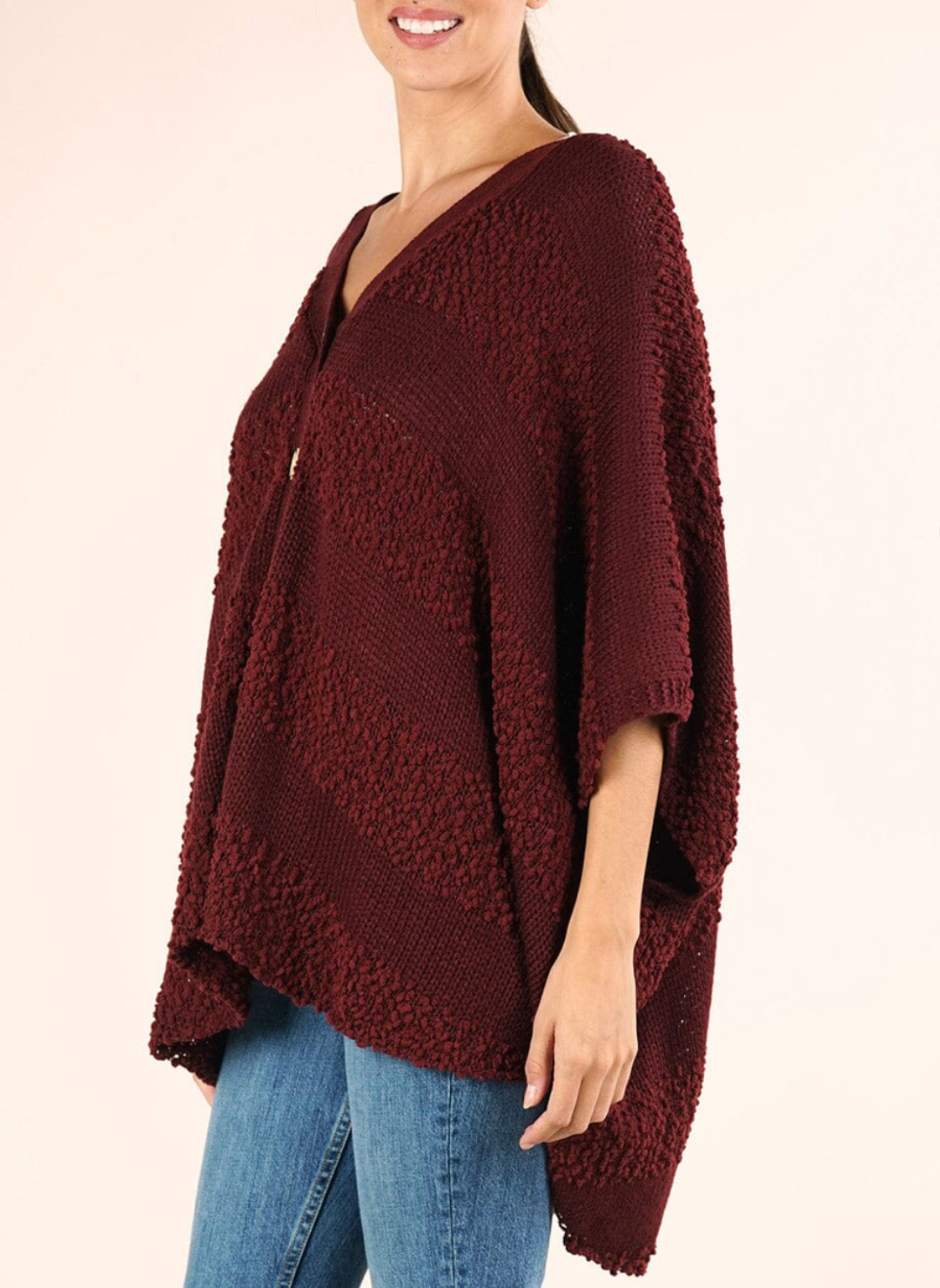 Woman wearing a burgundy poncho over a beige background
