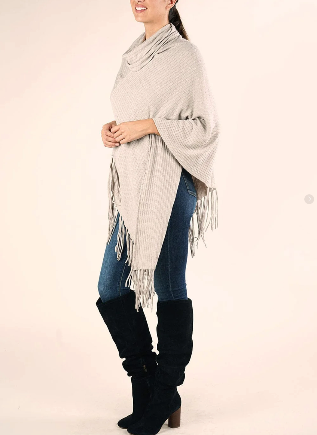 Woman wearing a light gray fringe poncho over a white background