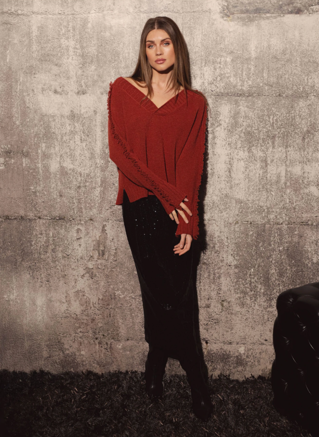 Model wearing Elan Falling Sweater in rust with fringe trim along sleeves and shoulders.