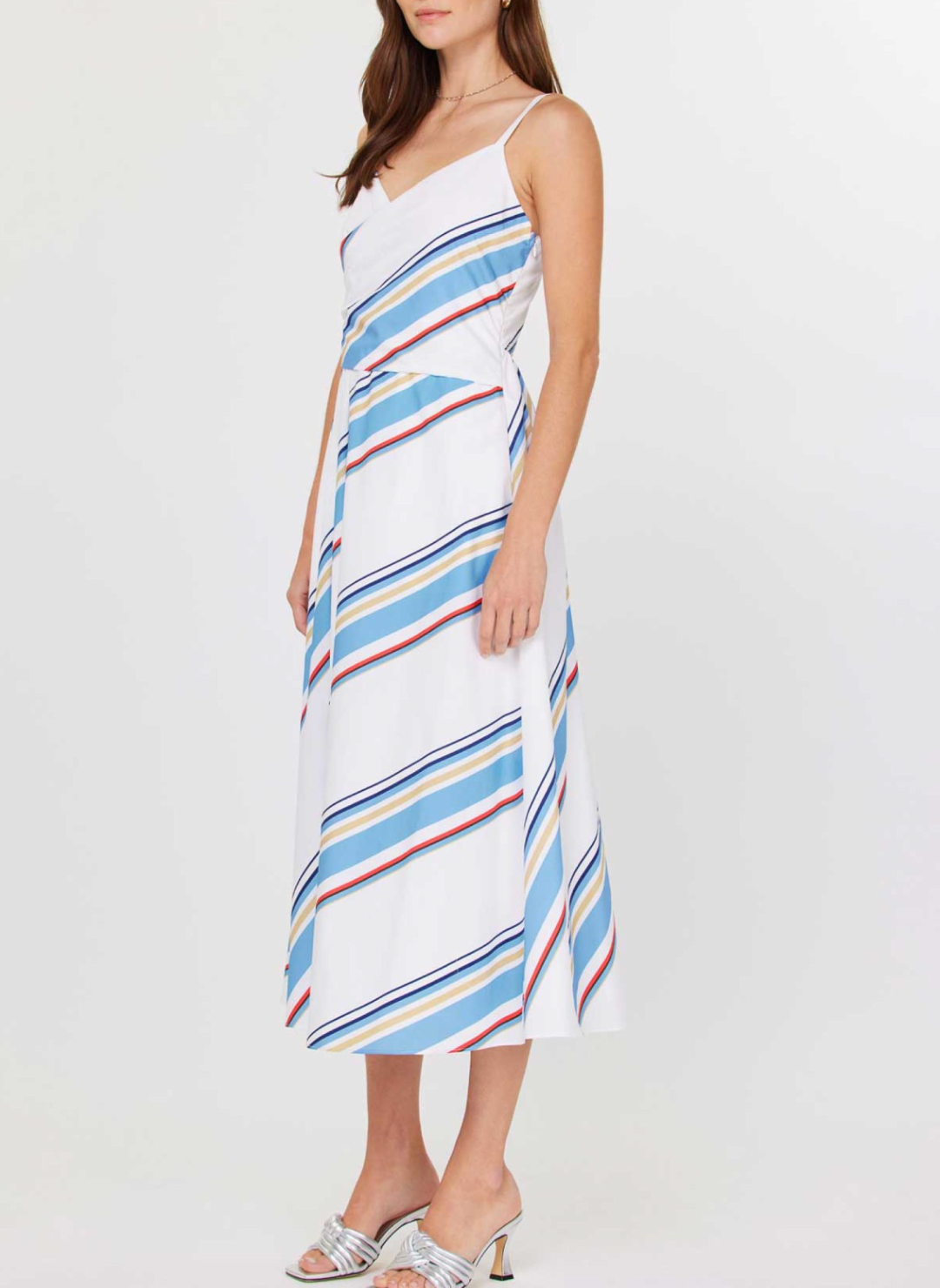Front and back views of the Current Air Juliette V-Neck Wrap Midi Dress: a white cotton poplin midi dress with adjustable spaghetti straps, V-neck wrap bodice, sky blue/navy/red/beige diagonal stripes, smocked back panel, side seam zipper, and self-fabric waist tie, modeled with silver slide sandals.
