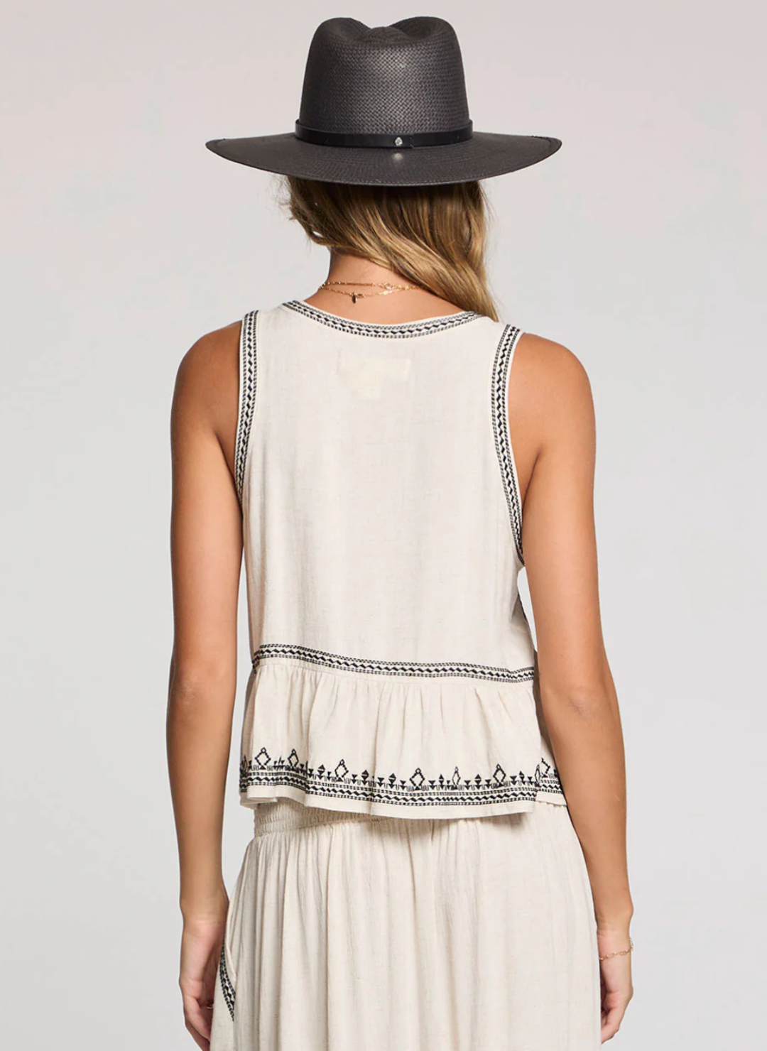 Back view of model wearing the Saltwater Luxe Quinley Embroidered Tank in cream with black embroidery, styled with the matching embroidered skirt and a wide-brim hat for a boho-chic summer look.