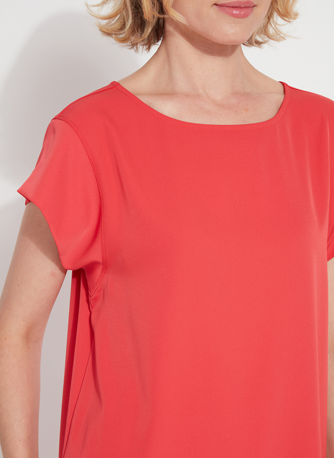 Woman wearing the Melodie Top in Coral Bloom from August Boutique Ripon; features flutter sleeves, scoop neckline, flowy drape, and keyhole back detail. Lightweight and perfect for warm-weather styling.