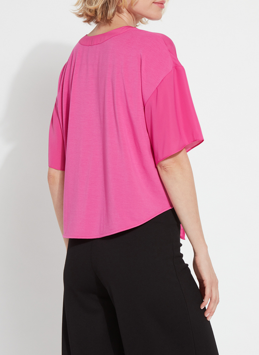 Back view of a woman wearing the Lyssé Cleo Tie Up Top in vibrant hot pink; features dolman short sleeves, v-neckline, and tie-front hem. Styled for comfort and polish, available at August Boutique Ripon.