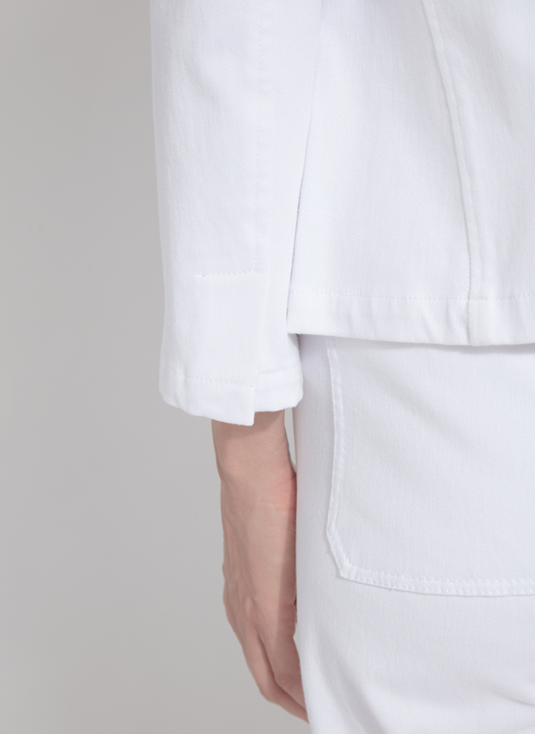 Close up view of the back sleeve hem of the white stretch denim blazer by Lyssé.