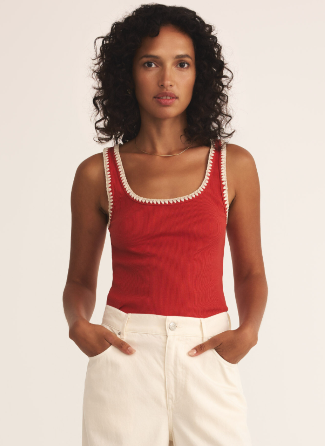 Woman wearing a red ribbed tank top with cream whipstitch trim on straps and neckline, styled with high-waisted ivory jeans – August Boutique Ripon summer top.