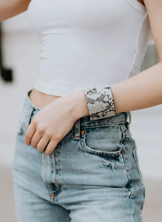 Full view of model wearing Snakeskin Cuff, white top, and denim bottoms. White background.