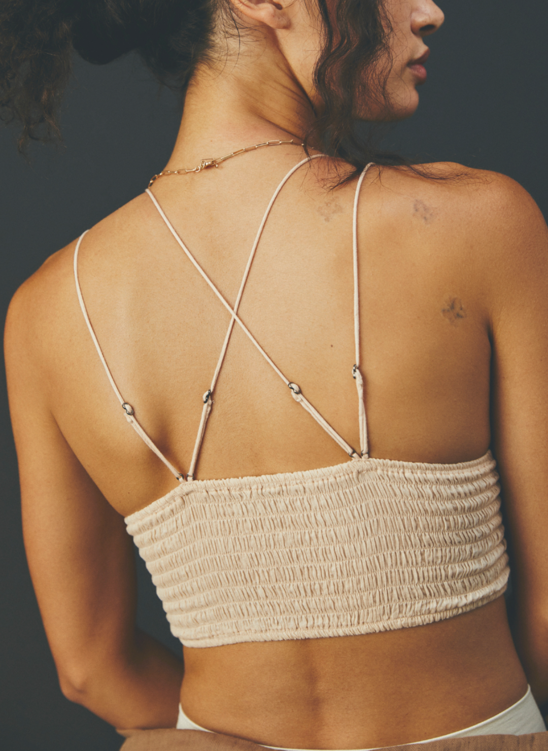 Model facing away wearing color Camel Adella Bralette showing the criss cross design of the straps on the back of the bralette.