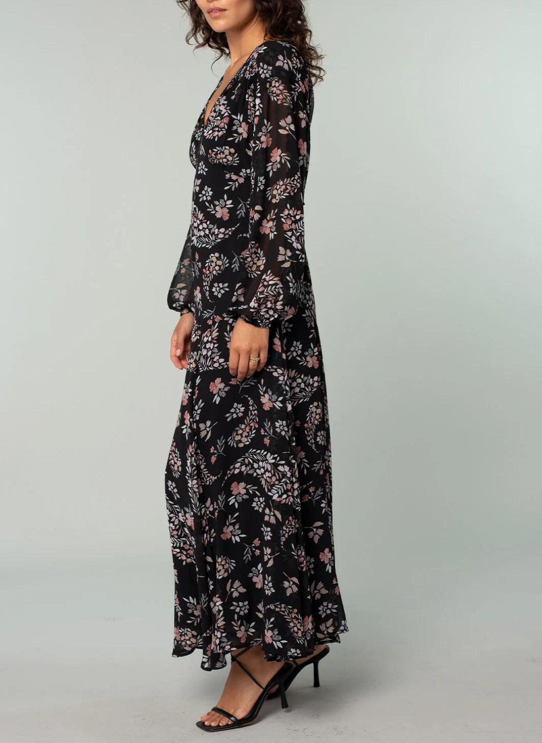 Model is giving a side view of the maxi dress showing the flow at the bottom