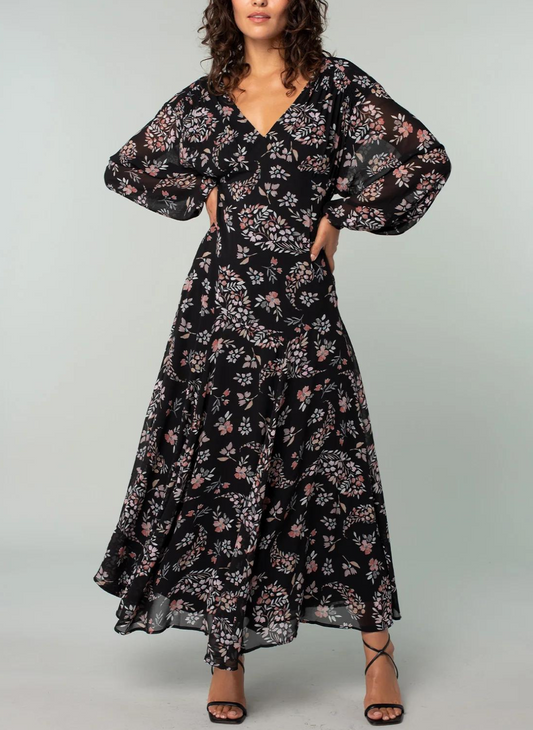Model is posing with hands on her hips in a maxi floral print dress.