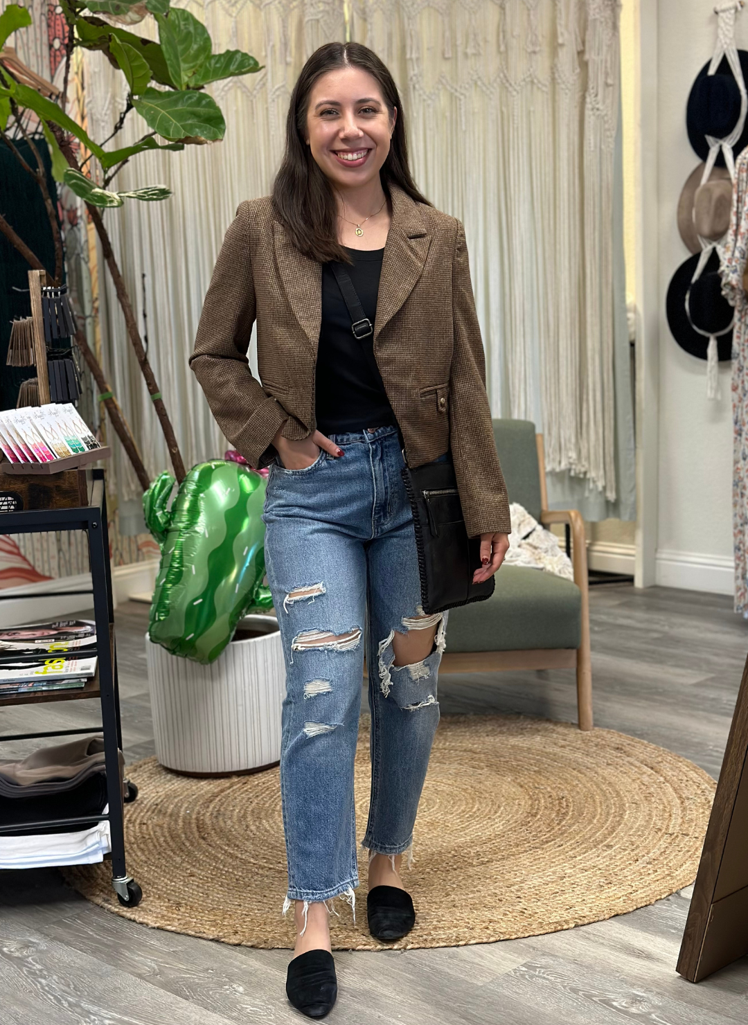 Front view of the model wearing the FM Distressed Mom Jeans that have holes in the front. Styles with a black tank and crop blazer top.