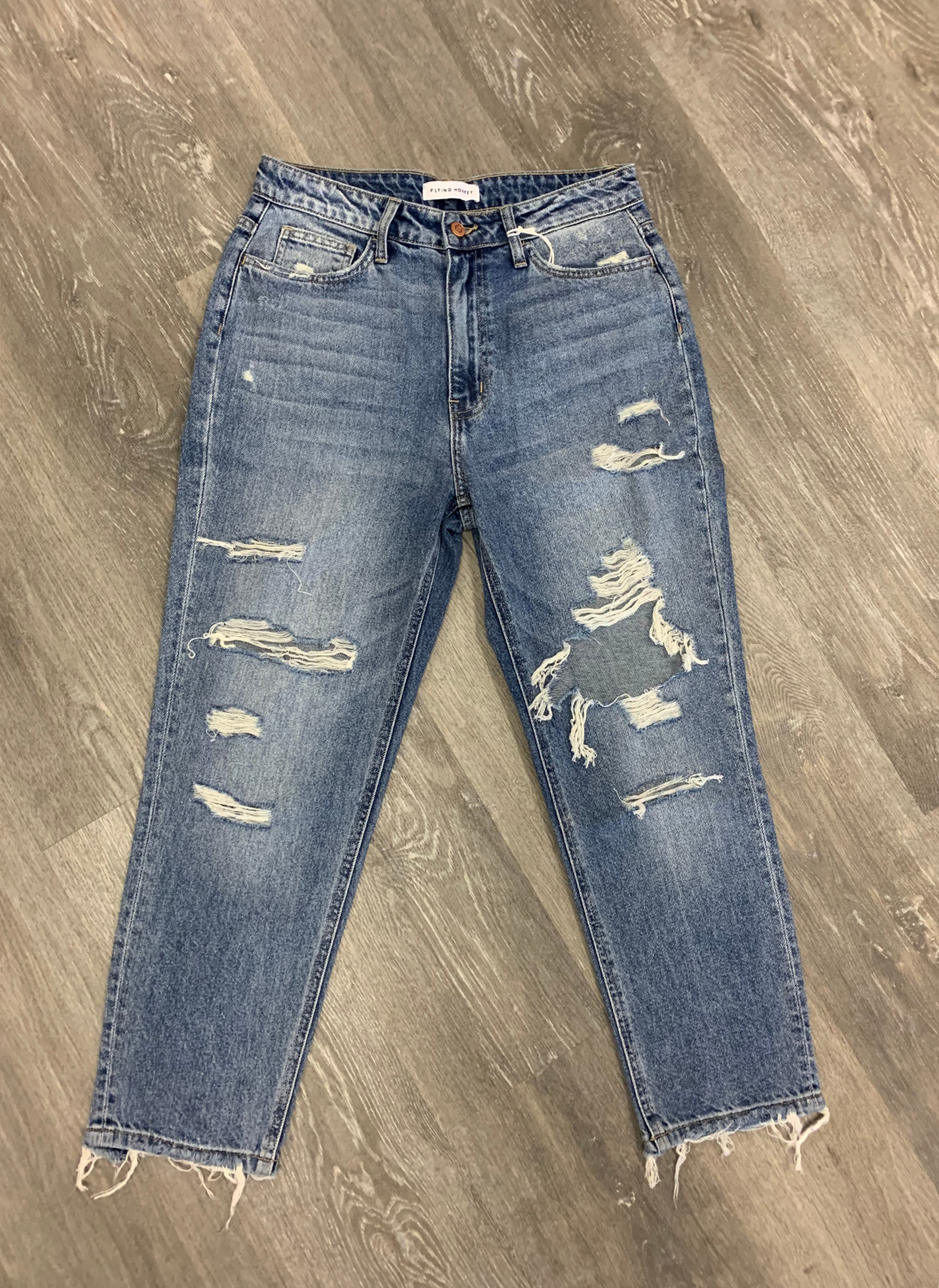 Front view of the FM Distressed Mom Jeans on the wooden floor highlighting the holes in the jeans.