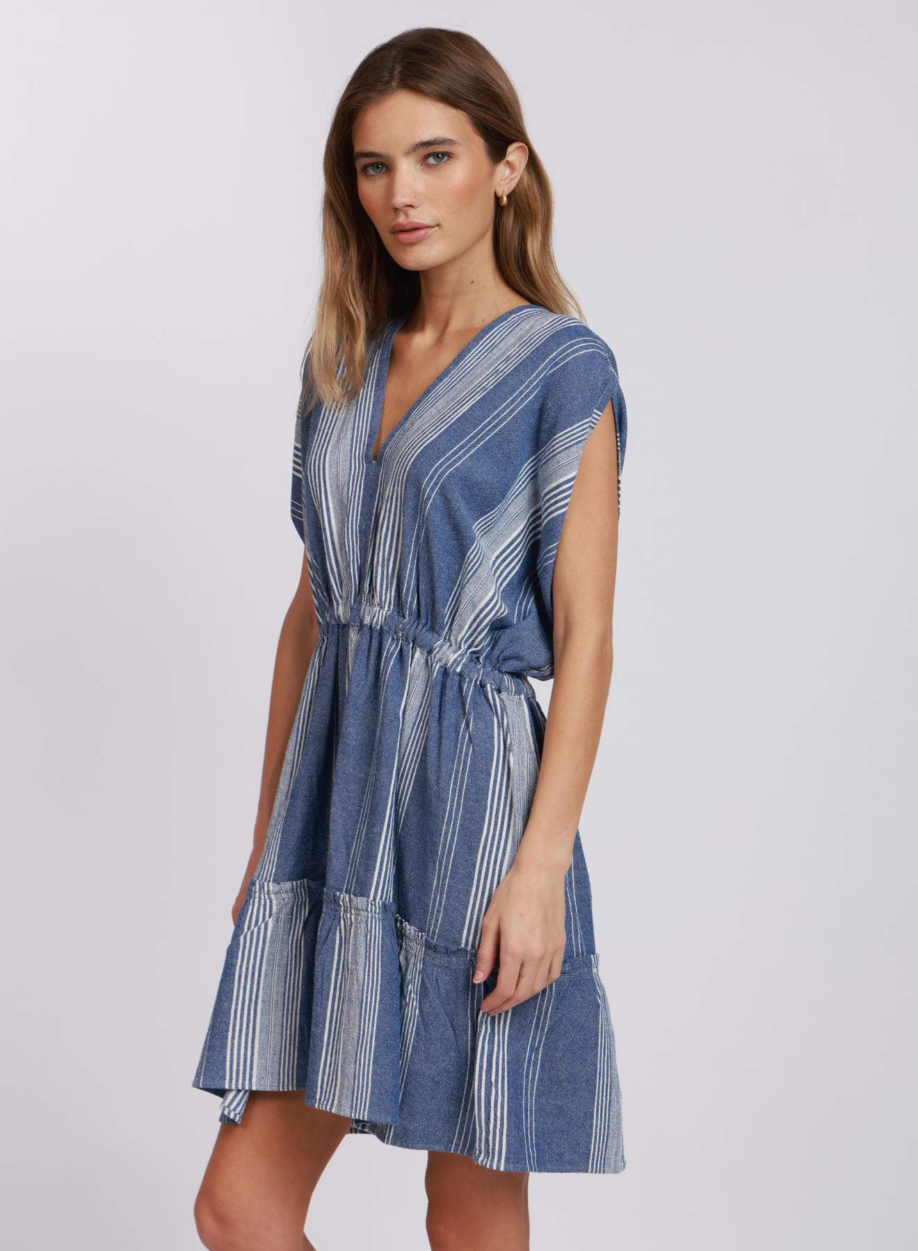 Dylan Malibu Stripe Dress – Indigo and white striped cotton dress with V-neckline, cap sleeves, elastic waist, and tiered hem, available at August Boutique Ripon.