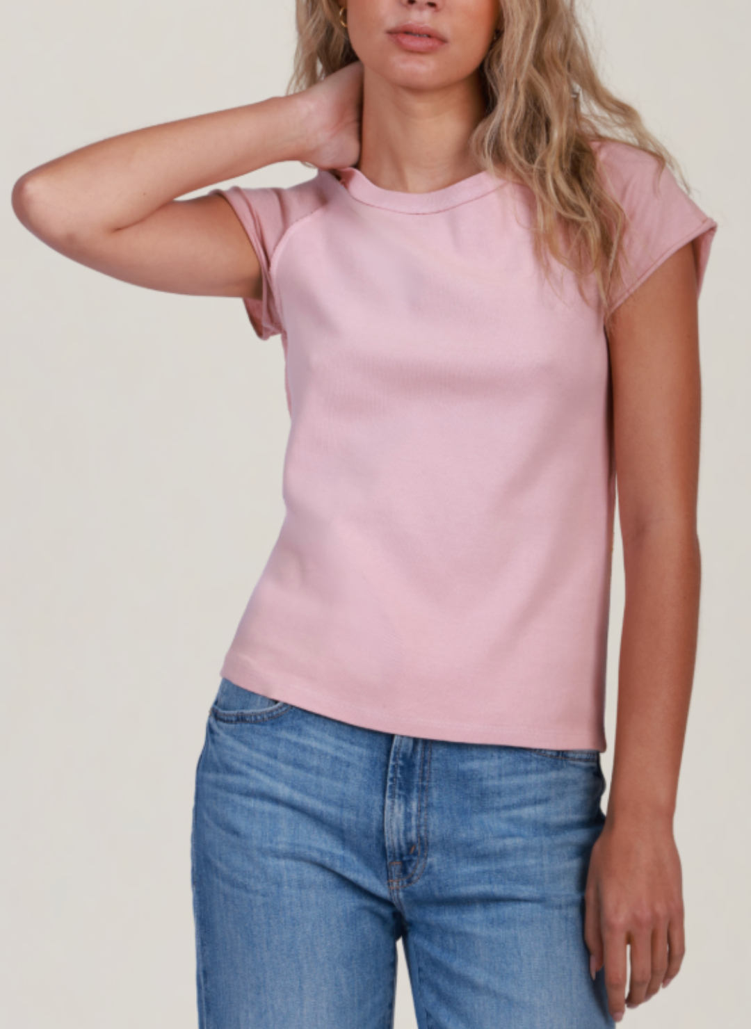 A person wearing a pink short-sleeved t-shirt and blue jeans.