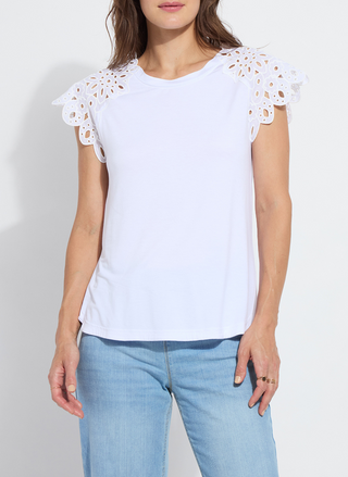Woman wearing the Lyssé Katarina Eyelet Sleeve Trim Top in white; features embroidered floral eyelet cap sleeves, crew neckline, and a rounded shirttail hem. Lightweight and feminine, available at August Boutique Ripon.