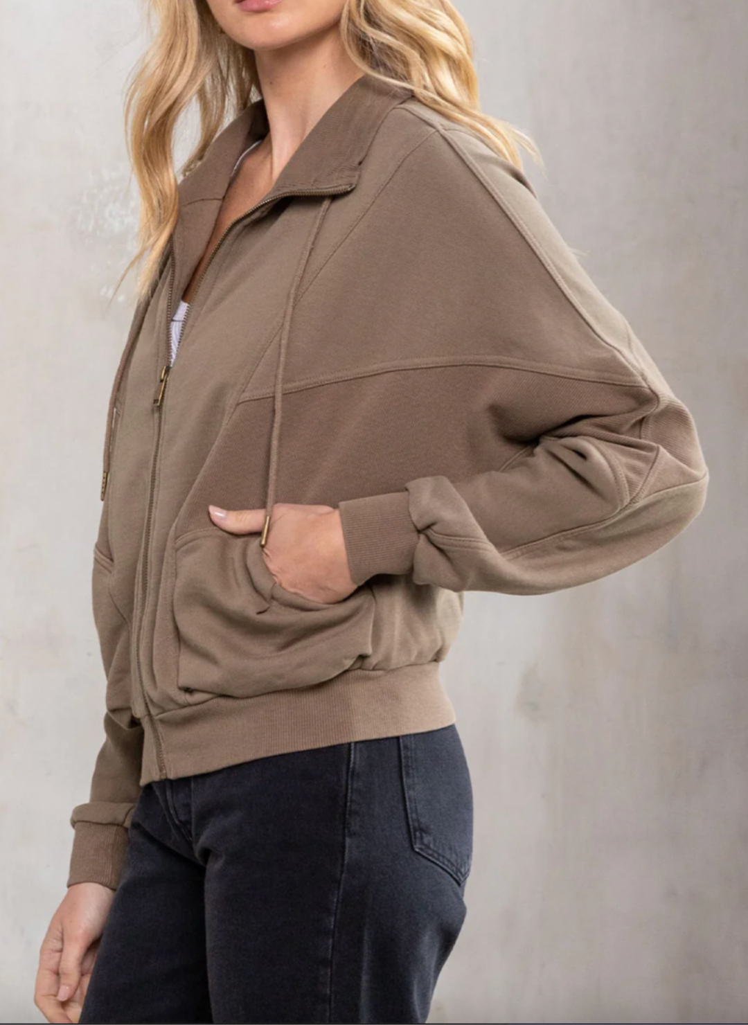 Side/ Front view of the model wearing the LS VIvian Vintage Zip Up Sweatshirt. Showing that it is a zip closure . The model is showing that the sweatshirt has pockets.