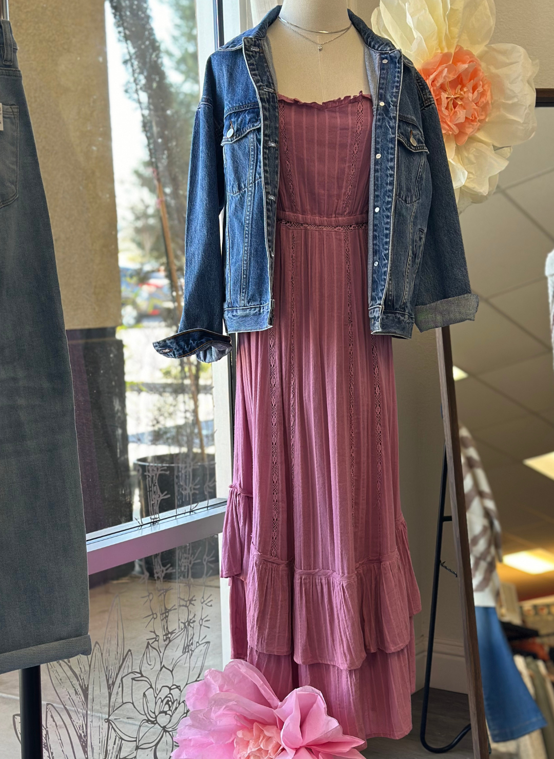 Full view of ZS Rose Maxi Dress paired with denim jacket. Model is standing in front window