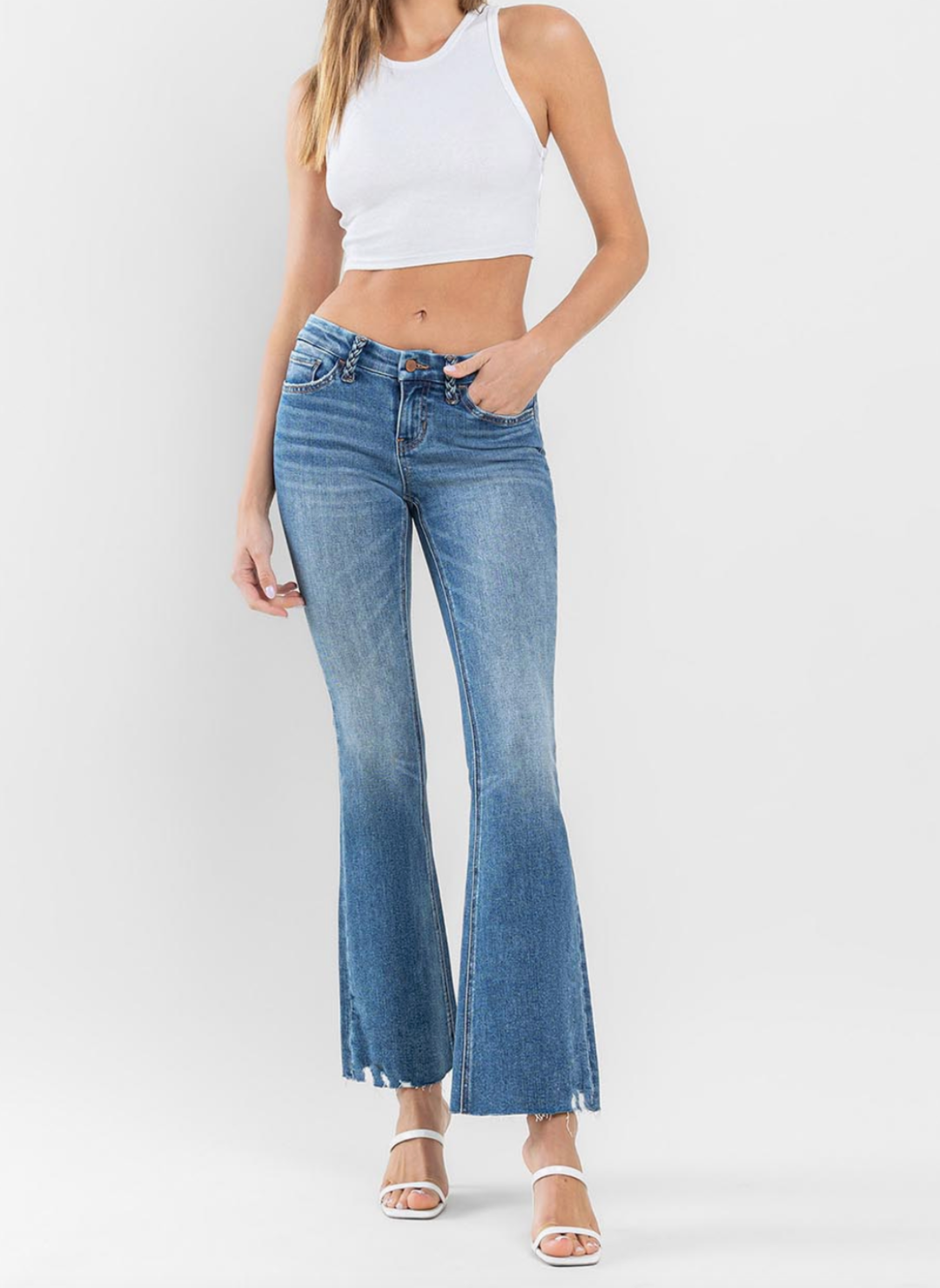 Model wearing FM Low Rise Flare jeans with braided belt loops and raw edge finish.