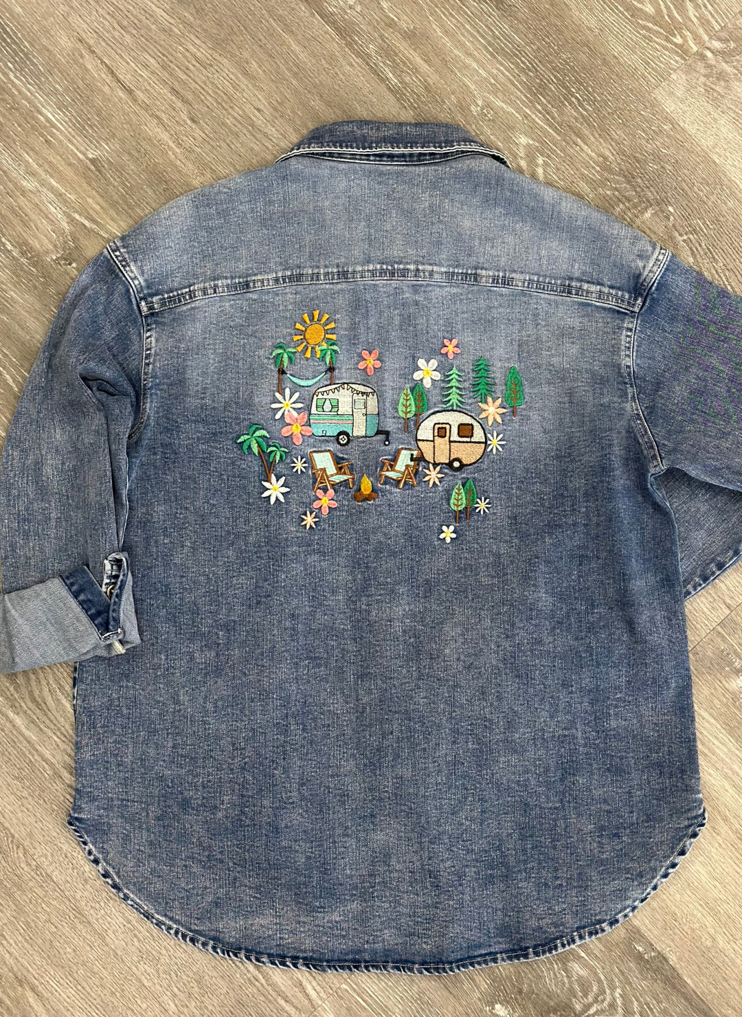 Back flat view of denim camper shirt with embroidered trailers, campfire, trees, sun, hammock, and flowers