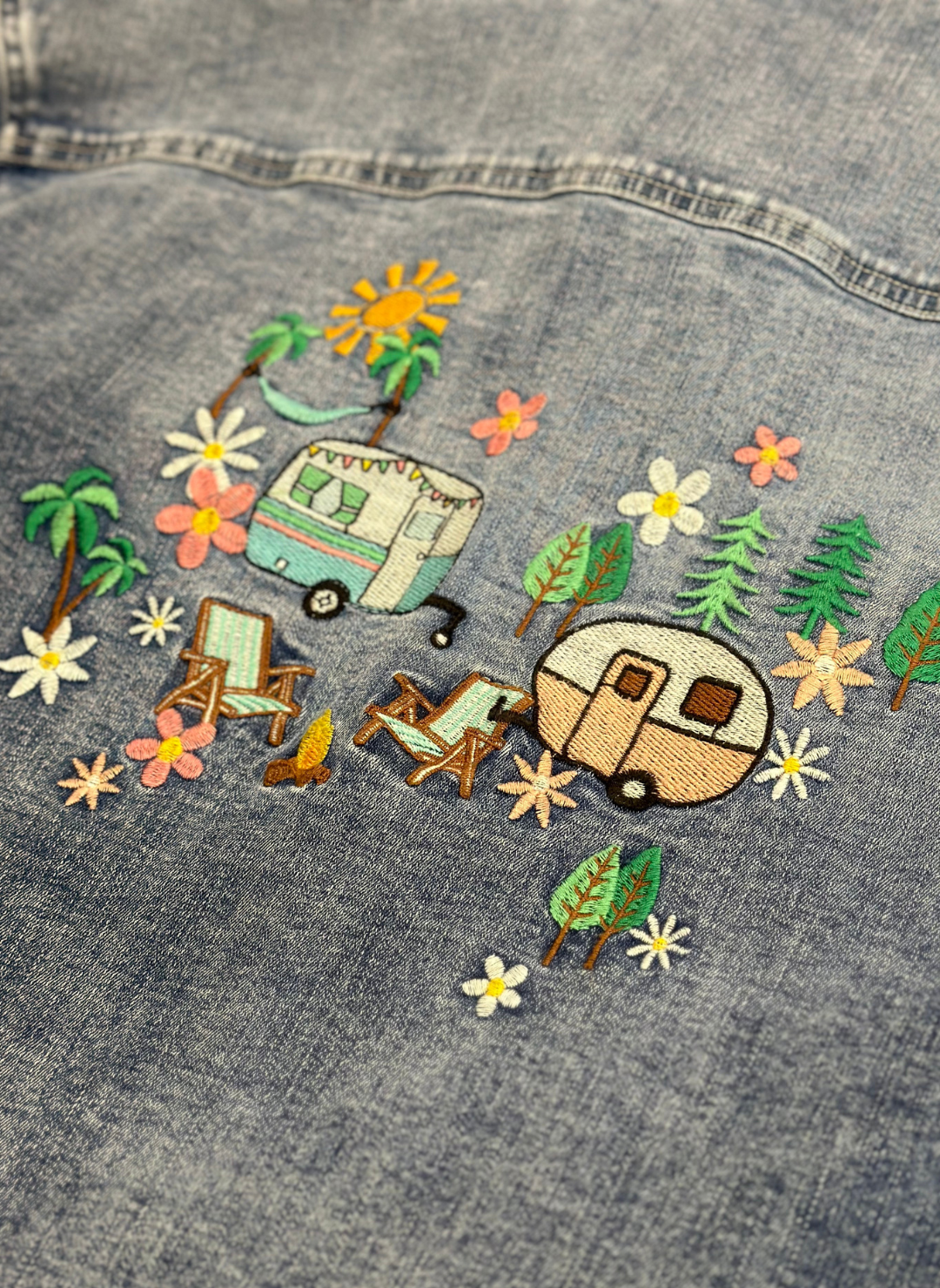 Close up back view of camper shirt with embroidered trailers, campfire, sun, hammock, trees, and flowers.