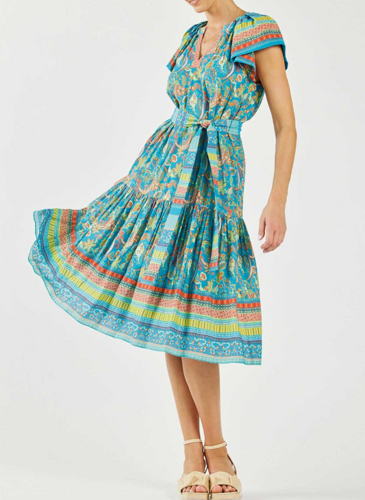 Model wearing colorful fiesta dress with ruffle sleeves, a cinching belt, and a multicolor border.