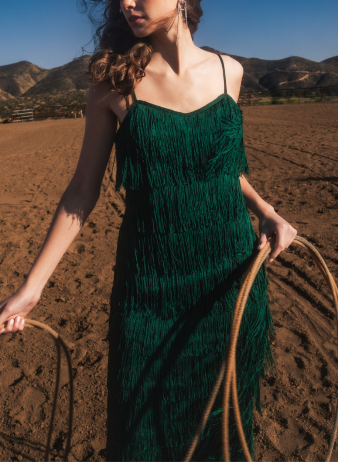 Up close view of model holding lasso and wearing Gi Fringe Strap Dress with vibrant green color and fun fringe.