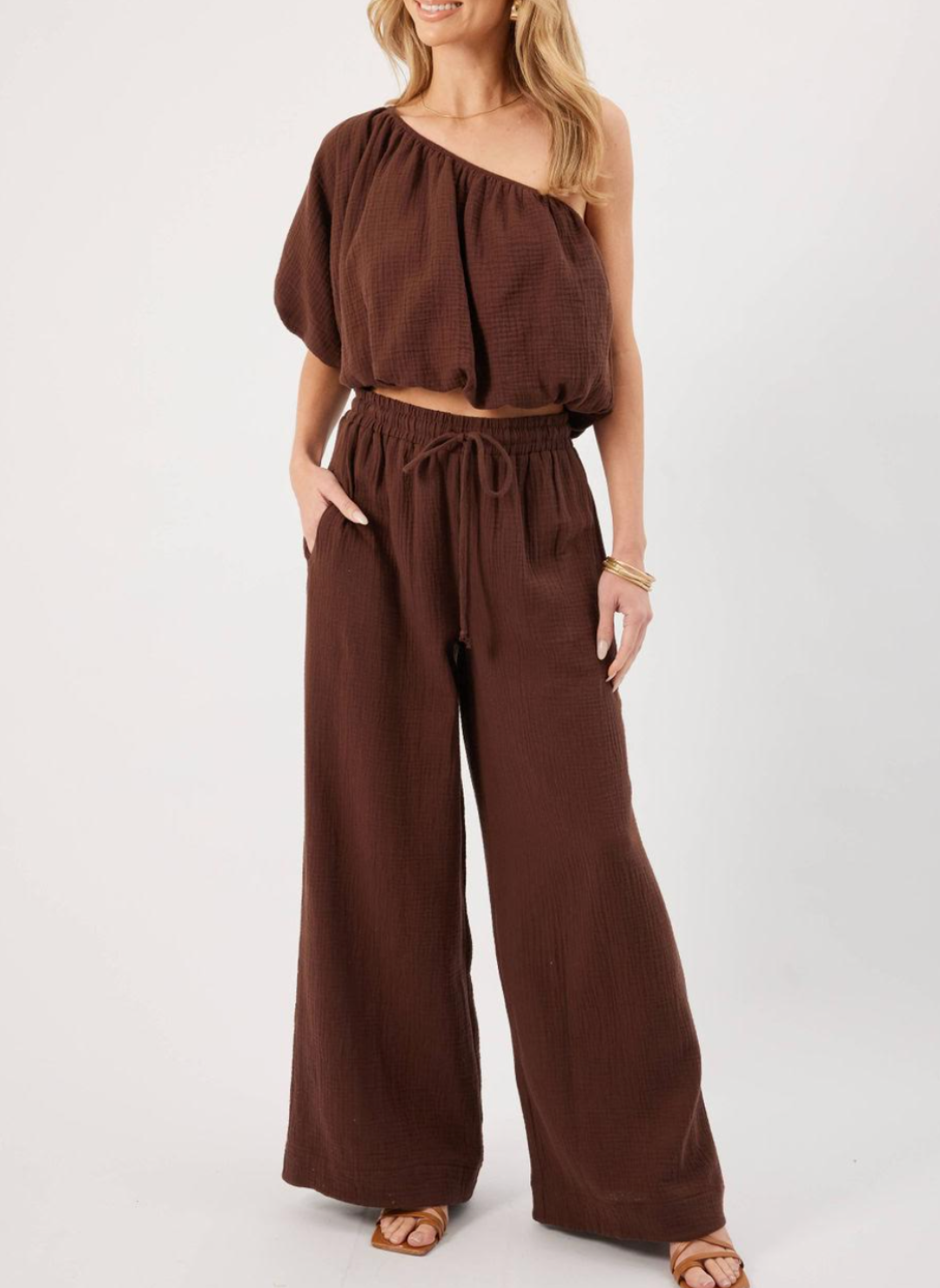  Model wearing brown KP Lina Top with one shoulder detail and bubble hem along with matching pants.