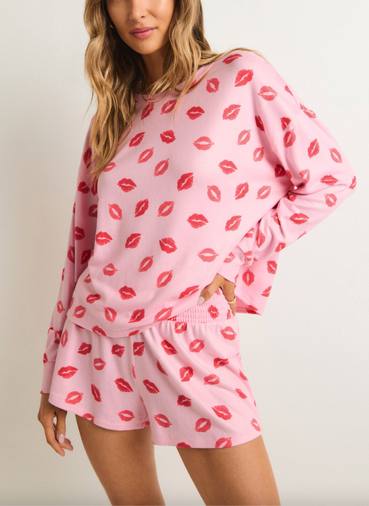 Model wearing a long sleeved top and short set with all over lips print in pink & red.