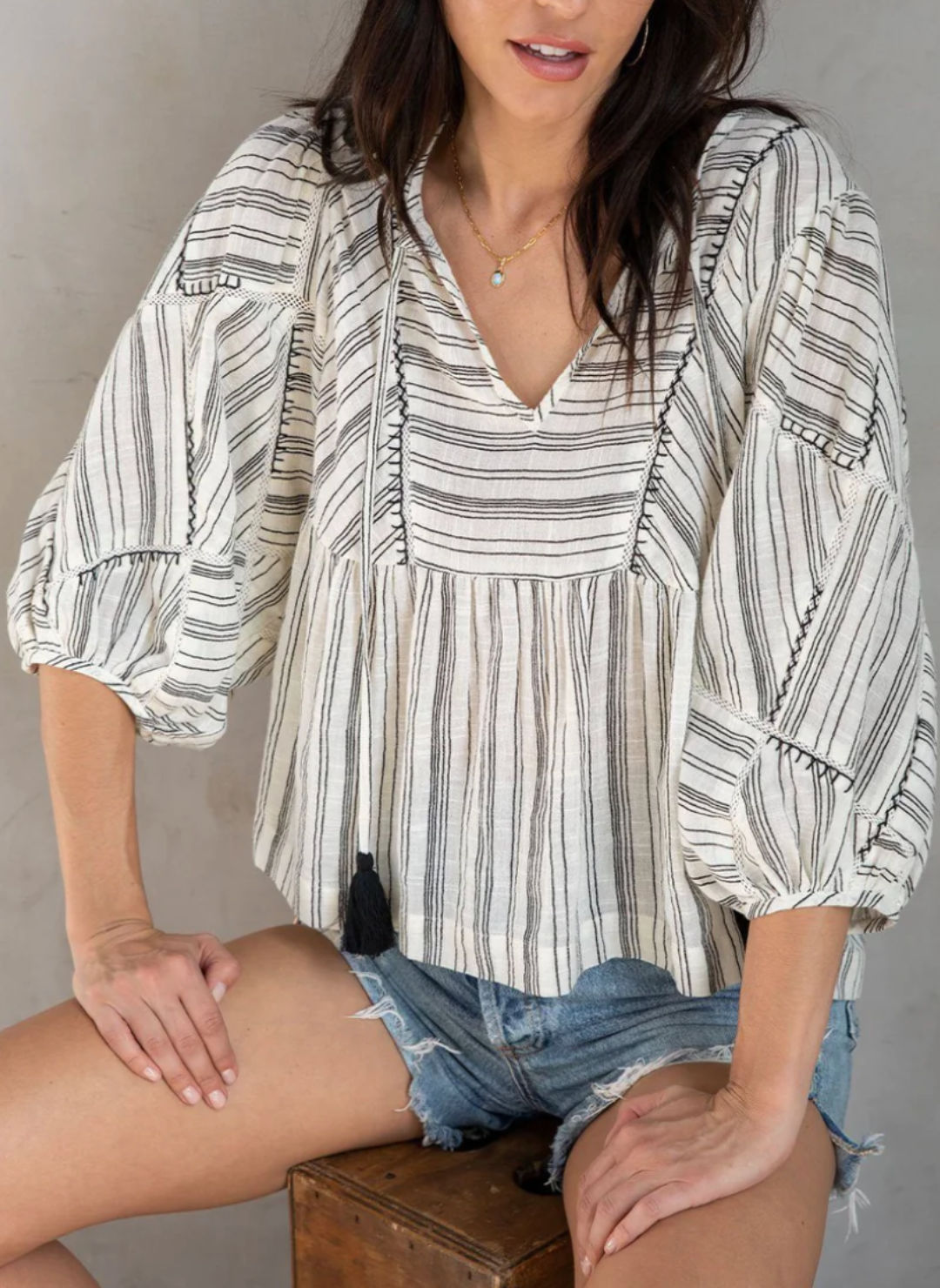 Front view of the model wearing the LS Printed Stripe Top showing the Hand embroidery pattern. Model is sittind down showing the length of the shirt and were it should fall at.