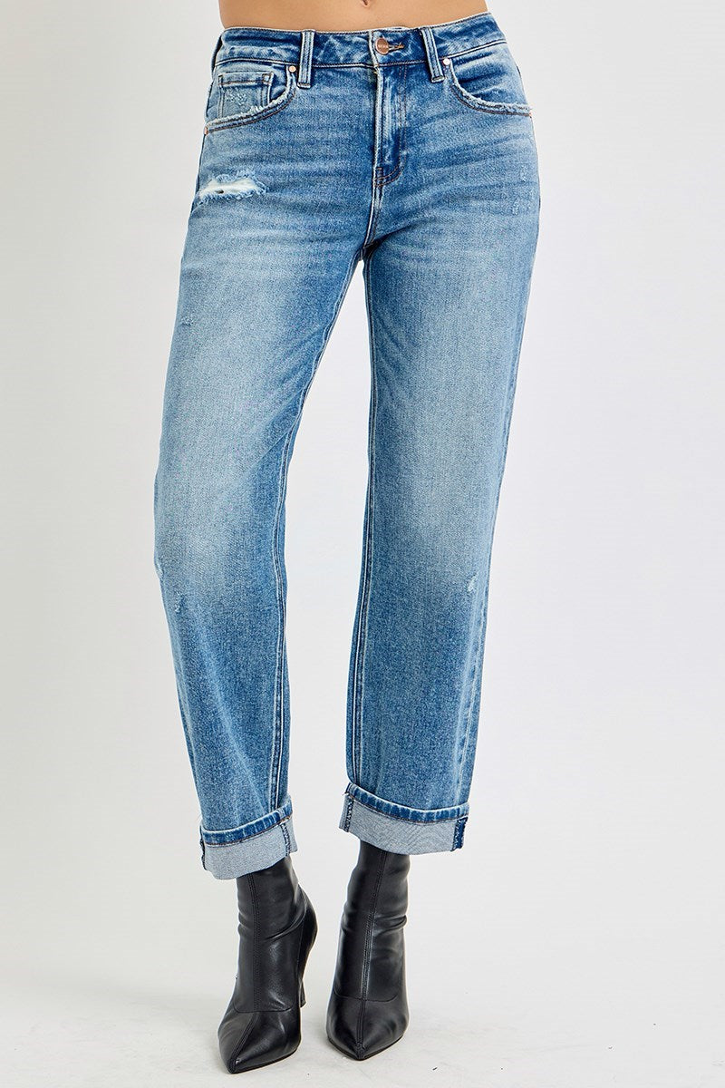 Front view of distressed denim jeans with left leg slightly bent, paired with black ankle boots.