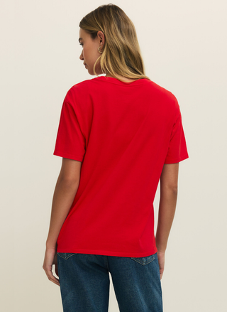 Person wearing a red t-shirt and blue jeans on a beige background