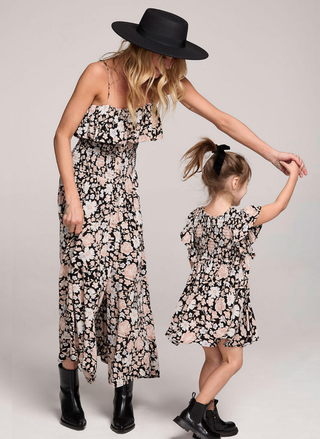 Woman and child wearing matching floral dresses on a plain background