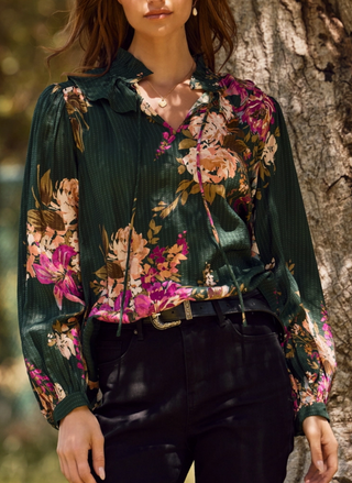 Close-up detail of ruffled neckline with tie accent and garden-inspired floral print on Oddi blouse